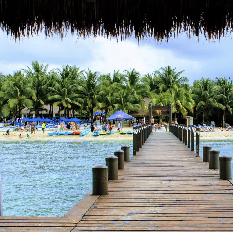 Beautiful view from a walking pier  of toursists lounging at the beach in Cozumel