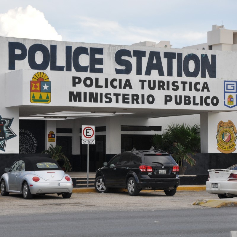 Cancun Police Station with cars parked out front and along the street.