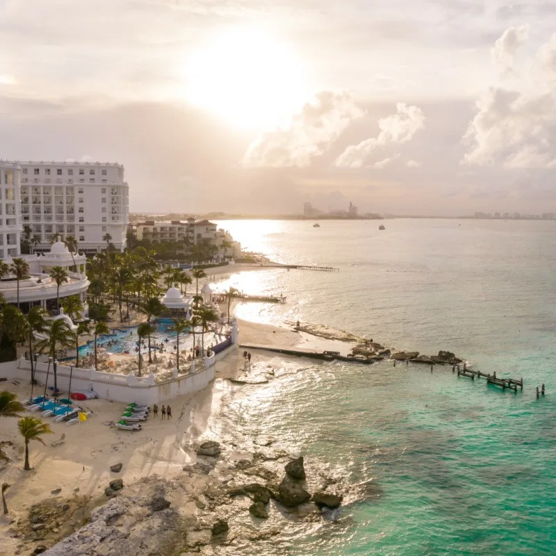 Cancun Resort on the water with the sun setting in the background.