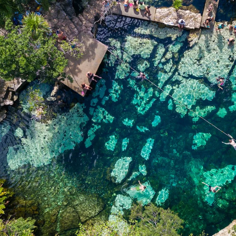 Cenote Azul in the jungle aerial view. People swim in clear water in a cenote that is in the jungle. Top view.