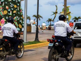 Featured 2 MUNICIPAL POLICE ON MOTORCYCLE IN COZUMEL WITH DECORATED CHRISTMAS TREE and walking tourists on a sunny day