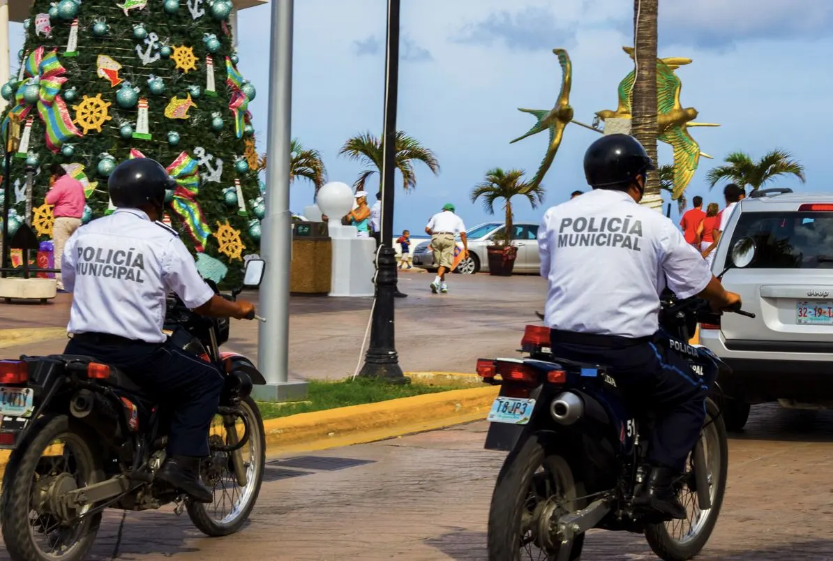 Featured 2 MUNICIPAL POLICE ON MOTORCYCLE IN COZUMEL WITH DECORATED CHRISTMAS TREE and walking tourists on a sunny day