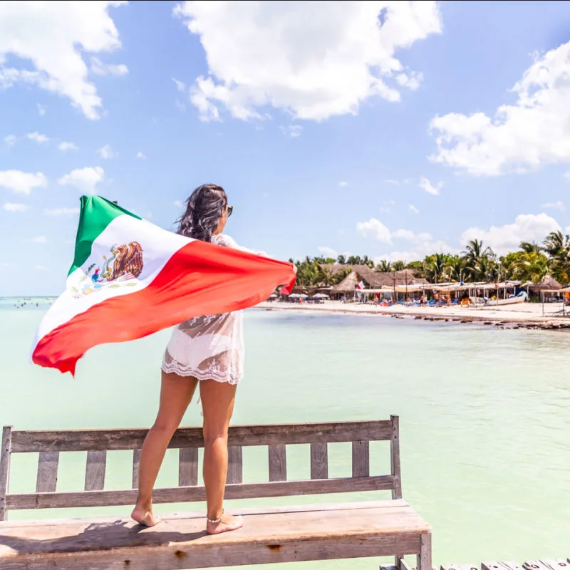 Woman holding Mexican flag in Holbox while enjoying beach