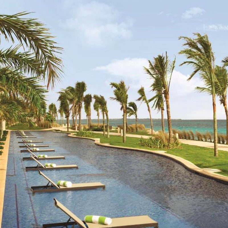 pool and loungers surrounded by palm trees at the Hyatt Ziva Cancun, family-friendly all-inclusive resort in Cancun.