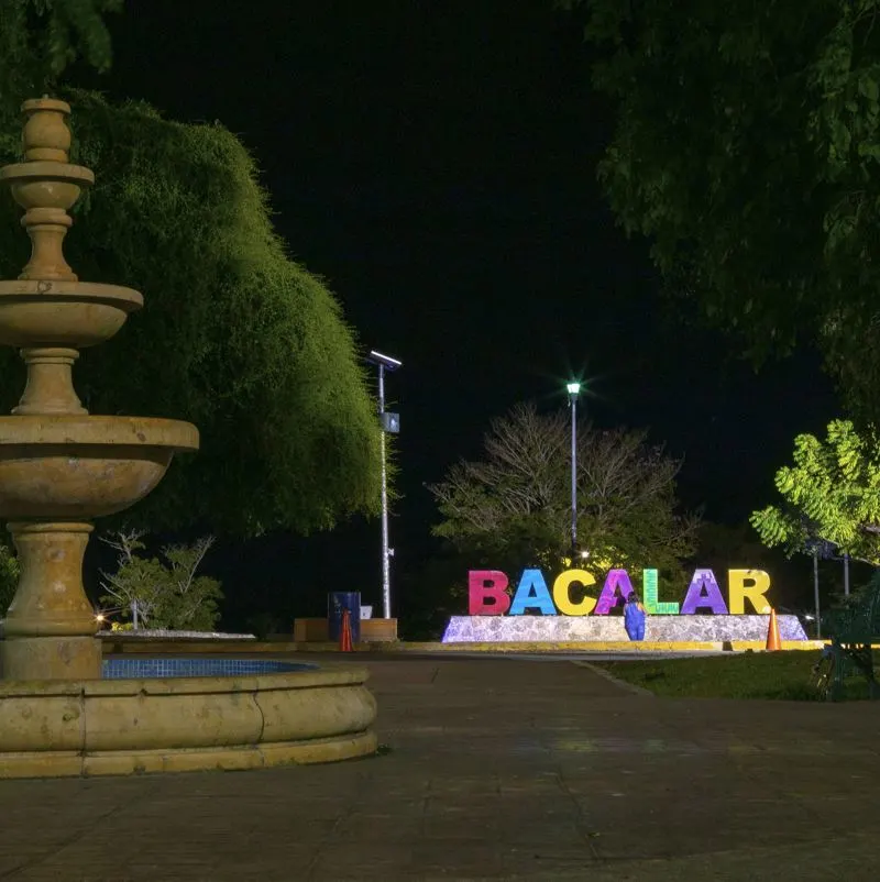 Bacalar town sign lit up in town main square at night.