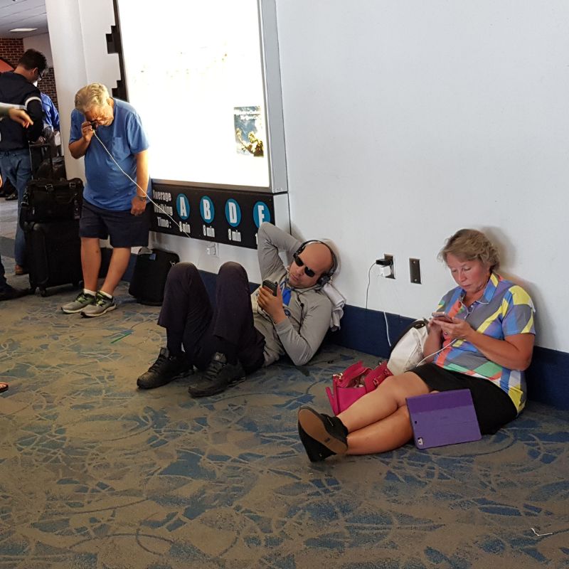 Passengers sitting in the floor and charging their phones in the corridors of the airport due flight delays