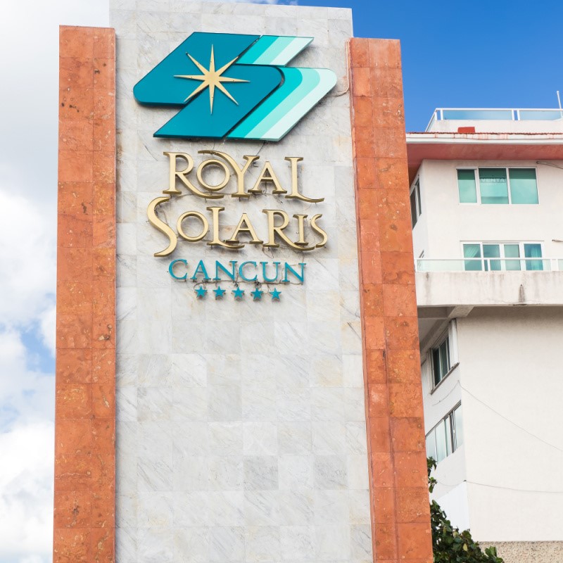 Sign in front of the Royal Solaris Cancun with a building in the background.