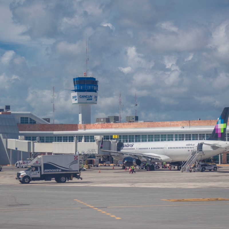 Cancun Airport with an airplane sitting on the tarmac and a truck nearby.