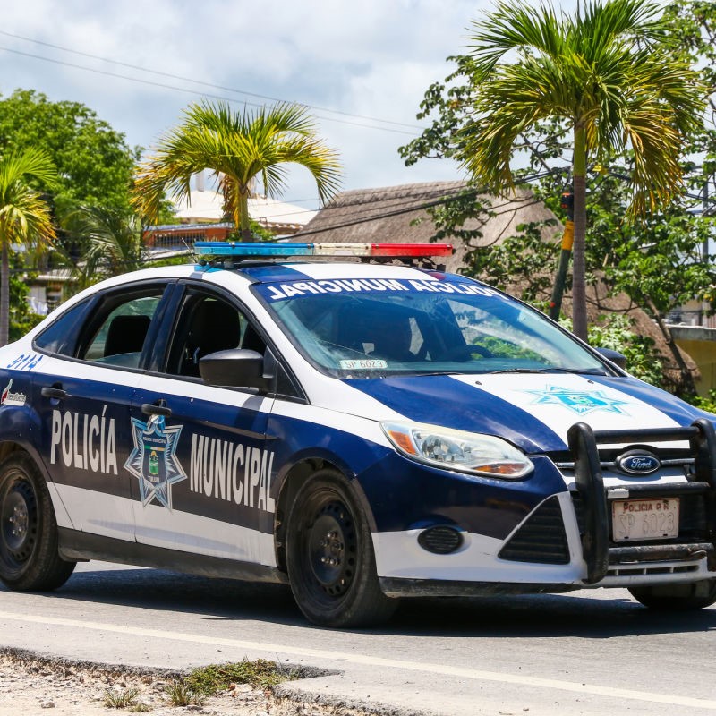 Police Car on Tulum Street with palm trees in the background.