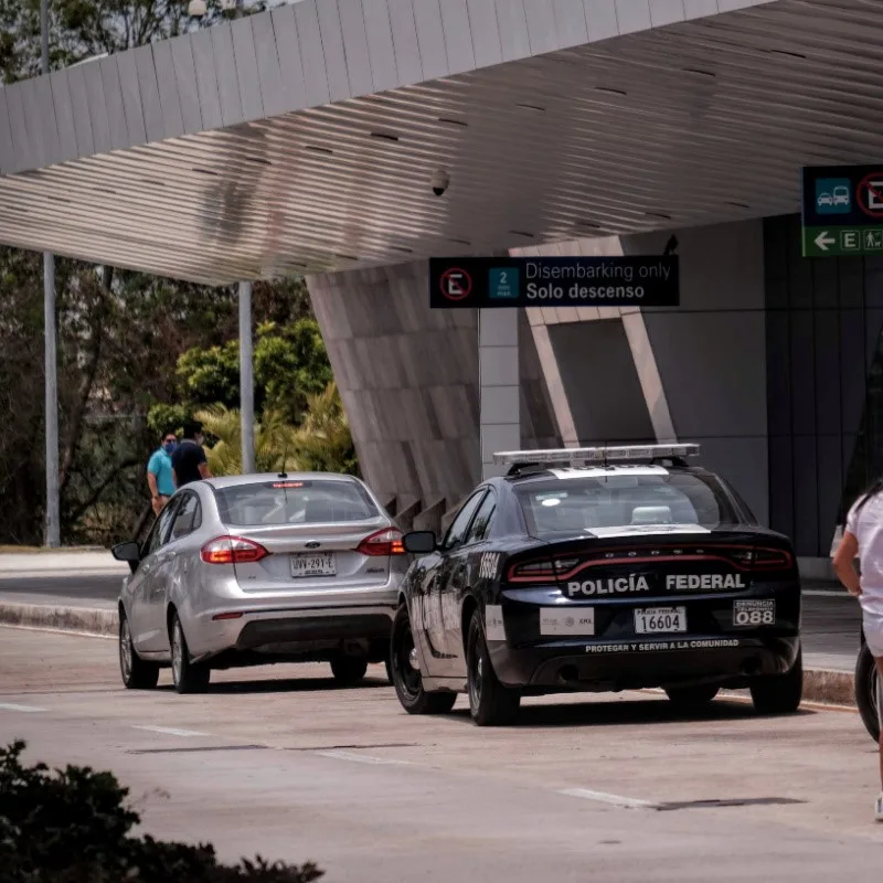 Police outside of Cancun International Airport parked with other cars in front of a building.