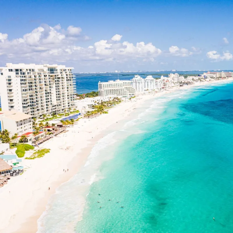 Resorts in the Cancun Hotel Zone with a wide stretch of white sand beach and aqua blue water.