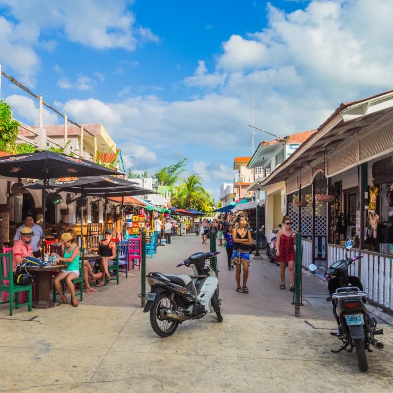 Street Filled with Restaurants and Shops in Isla Mujeres, Mexico, with people eating and walking in the background.