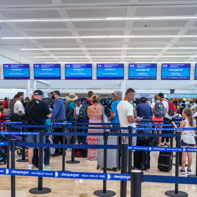 Tourists standing in line and Checking in for flights at Cancun Airport.