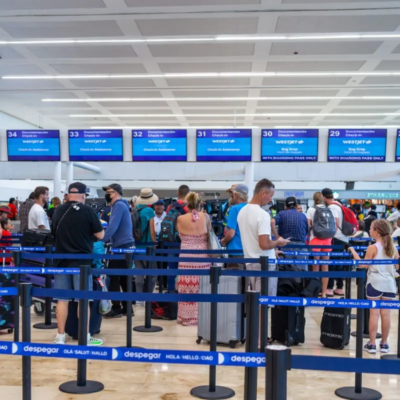 Tourists standing in line and Checking in for flights at Cancun Airport.