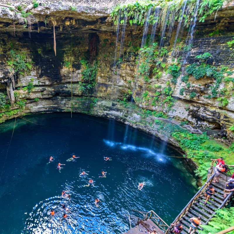 tourists swimming in a cenote in Mexican Caribbean during the day.