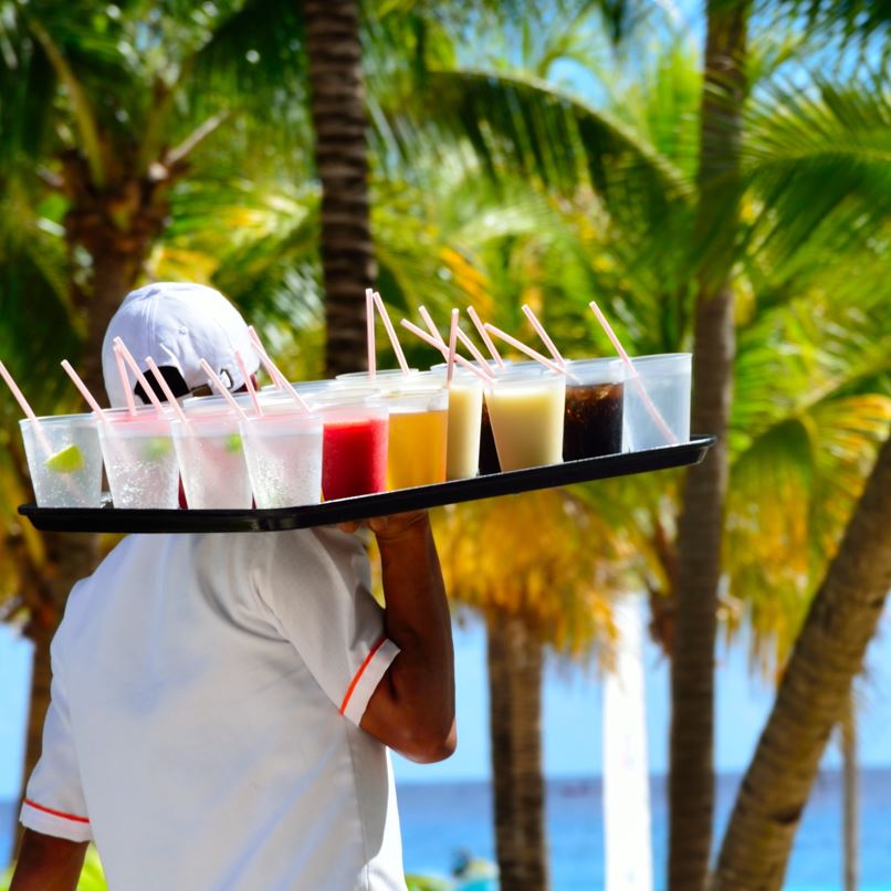 A waiter walks a tray of drinks to the beach in Cancun