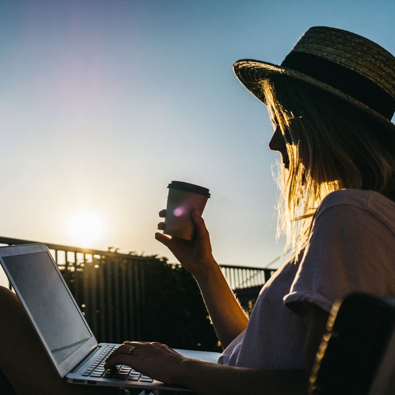 Woman drinking coffee and using laptop on balcony in mexico