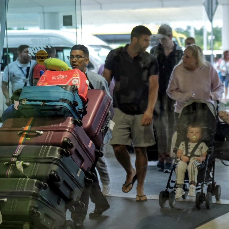 travelers moving luggage at cancun airport