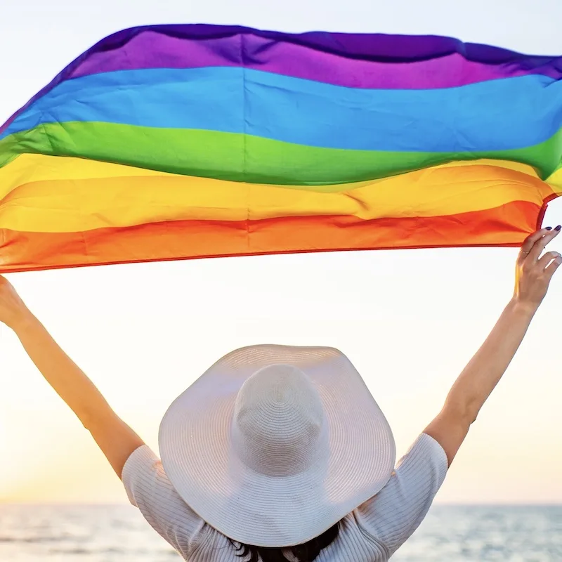 Woman holding up an LGBTQ+ flag in Mexico