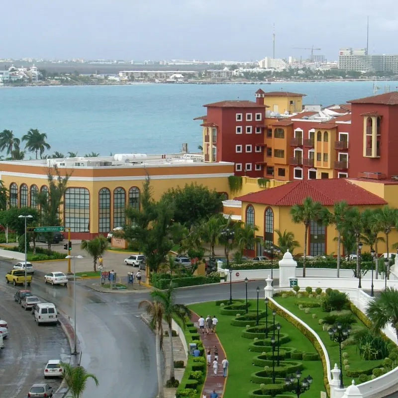 City View of Cancun with People Walking Around and a Building and Water in the Background