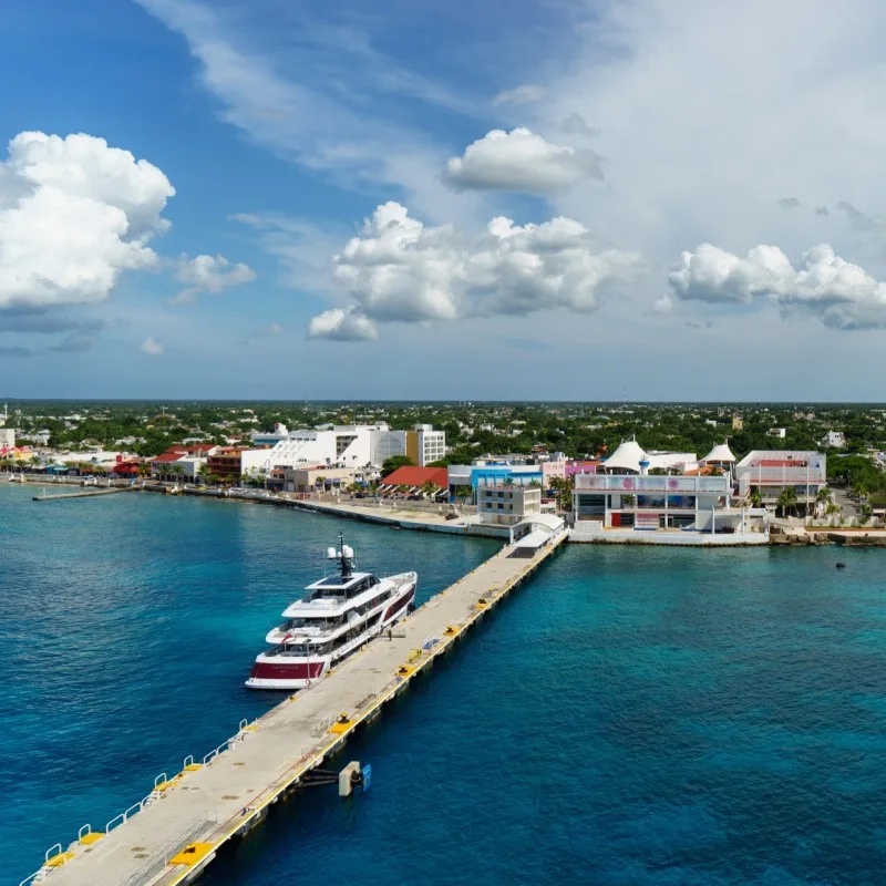 Cruise Ship Pier With a Boat Next to It and Buildings in the Background In Cozumel, Mexico