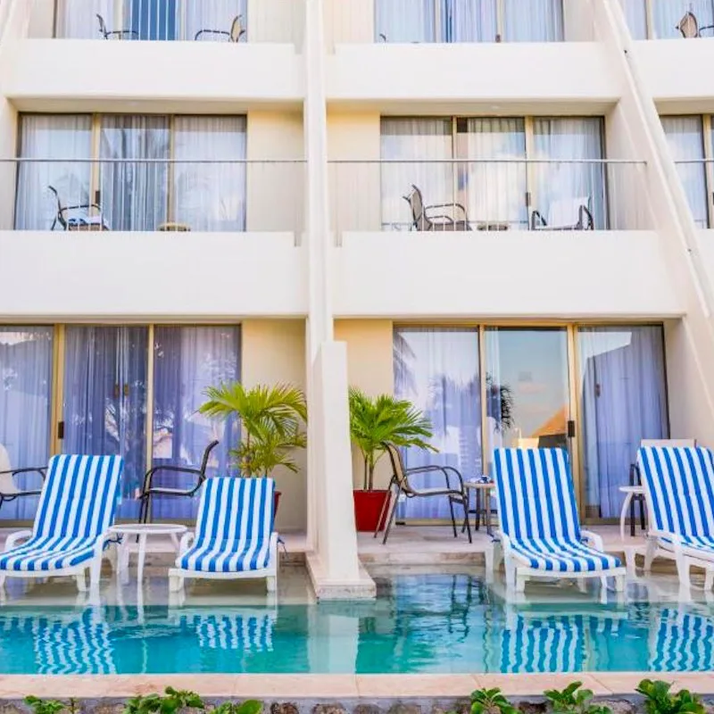 lounge chairs by swim-up pool outside of rooms at Grand Park Royal Cancun during the day.