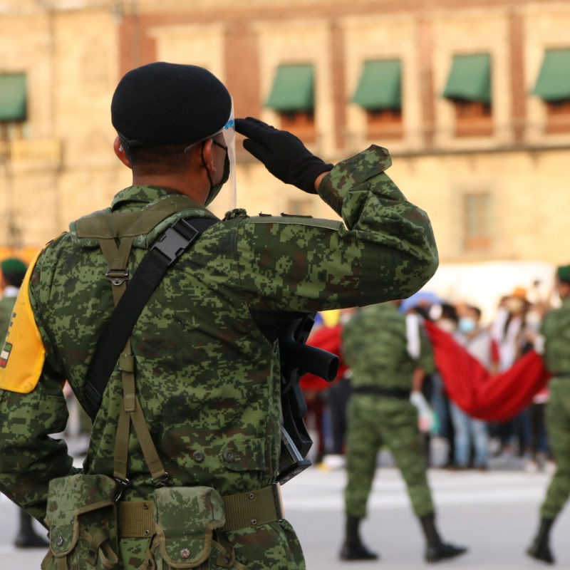 Armed official saluting the Mexican flag
