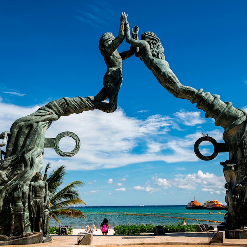 Mayan Portal, bronze monument on the Playa del Carmen Riviera symbol of new life and prosperity for the Mayan civilization of Yucatan. Image during the day, beach and blue skies behind the statue.