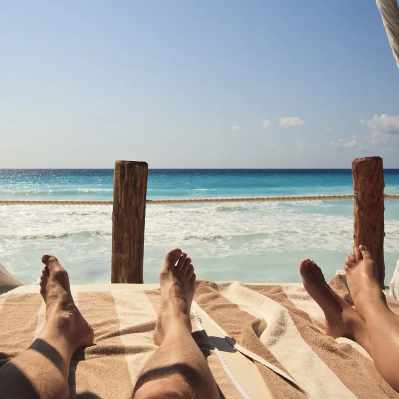 Tourists Relaxing on a Beach Bed Looking Out at the Caribbean Sea in Cancun, Mexico