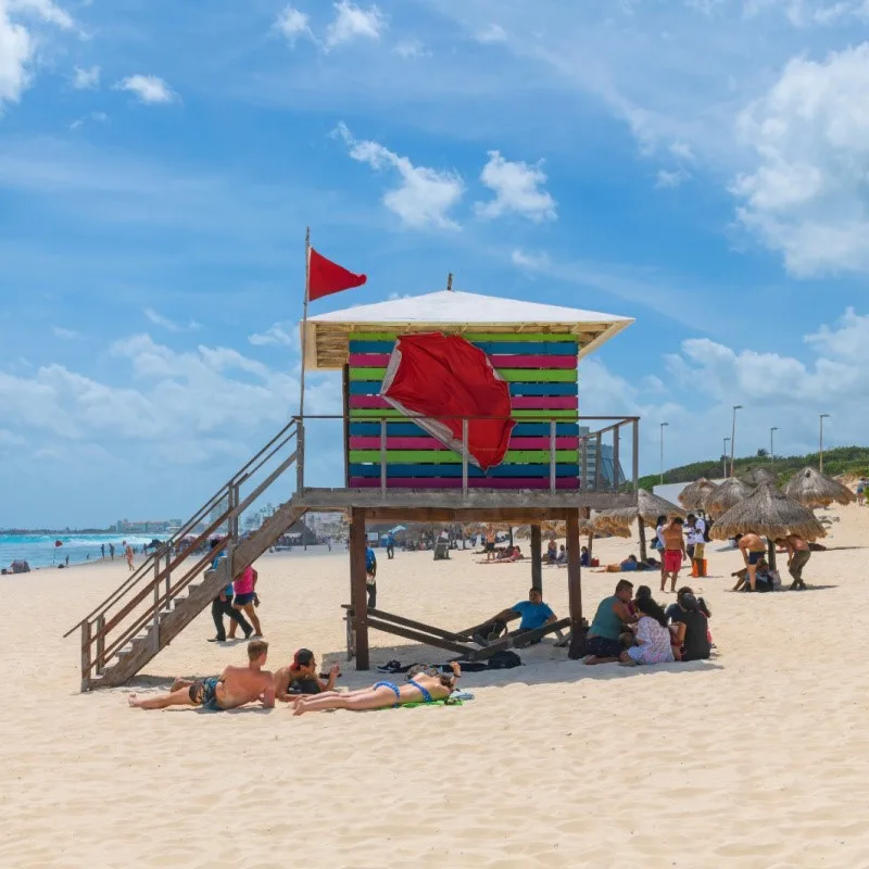 Tourists Surrounding a Lifeguard Station with a Red Flag Warning