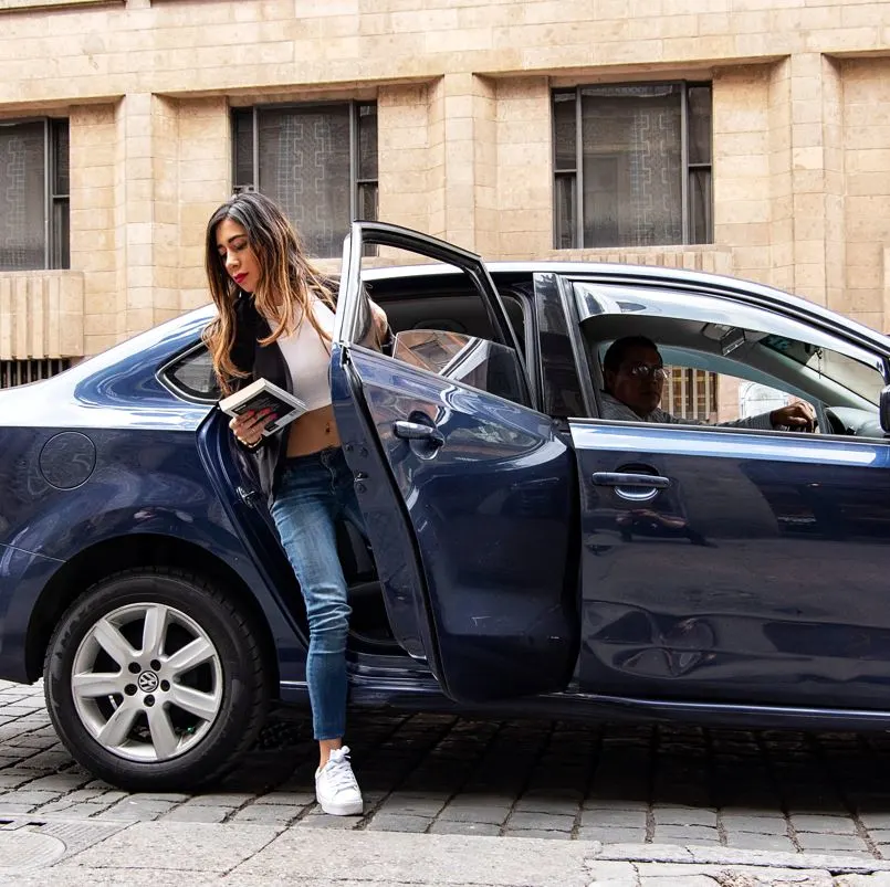 Woman stepping out of a vehicle, uber driver waiting for her to exit vehicle completely