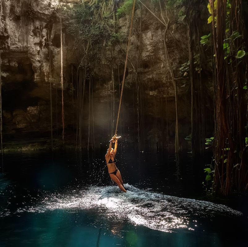 Woman winging into a cenote in mexico