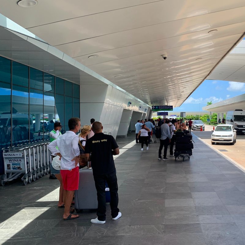 tourists and drivers at Cancun International Airport during the day.