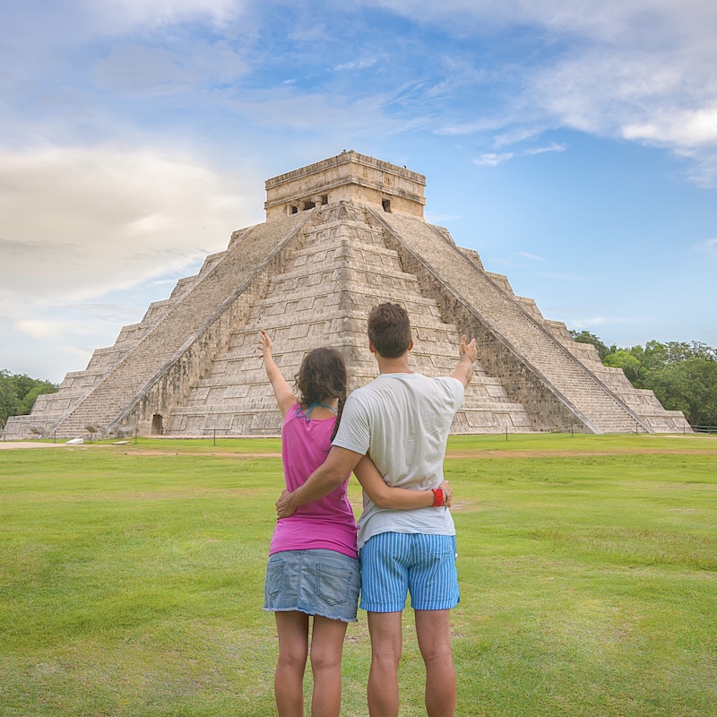 couple at chichen itza admiring a large pyramid 