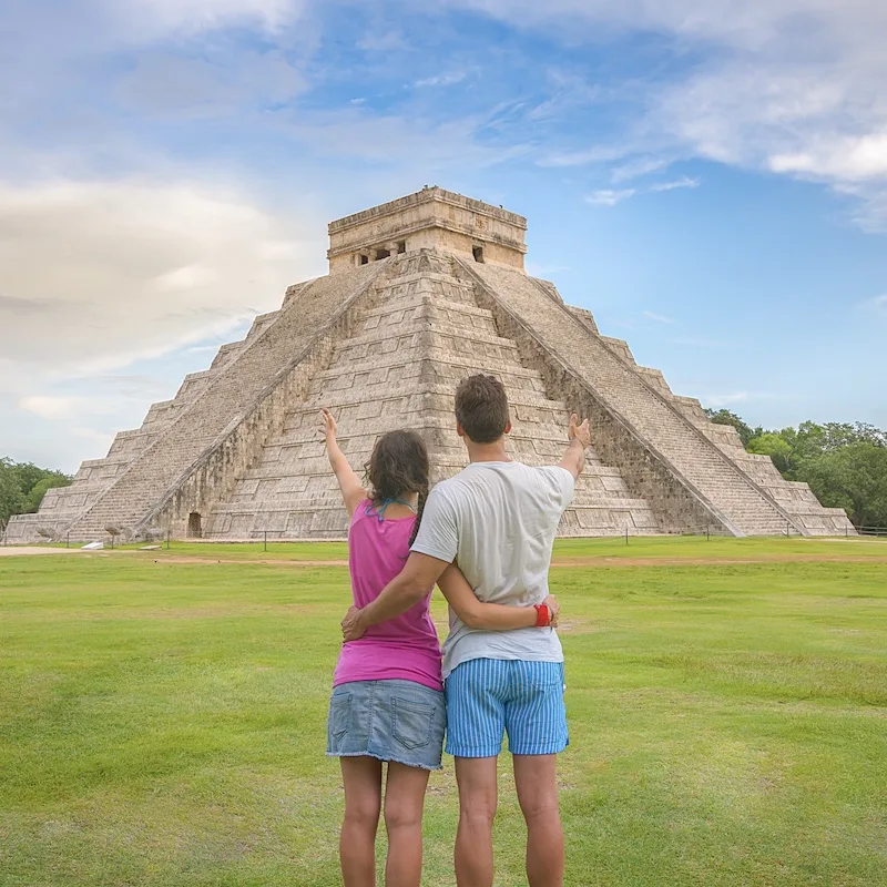 couple at chichen itza admiring a large pyramid 