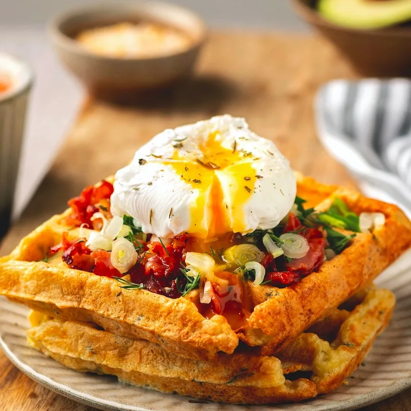 poached egg on belgian waffles, coffee, tasty breakfast, close-up.
