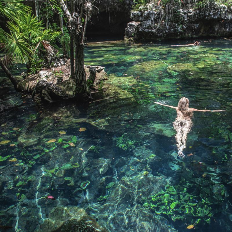 young woman swimming in a cenote in mexico