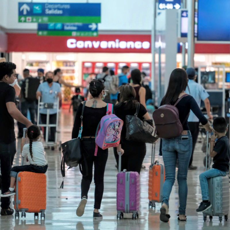 Crowd of passengers in Cancun International Airpot with shops in background 