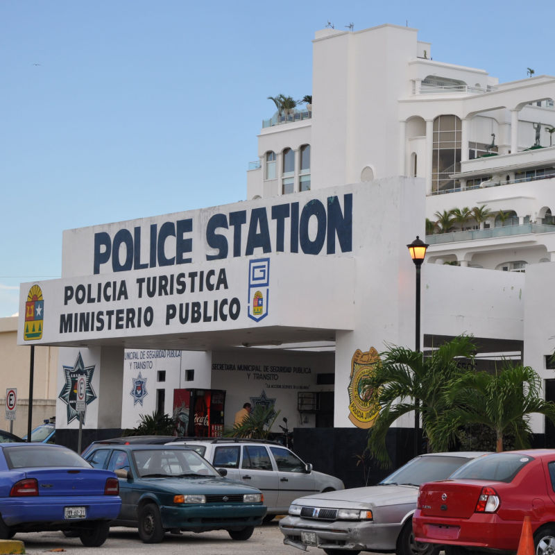 A Cancun jail with police cars and vehicles parked out in front