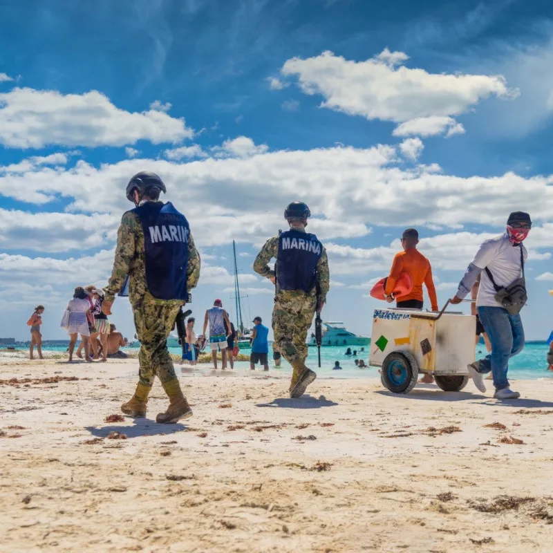 Military Officials Walking on a Busy Beach in Cancun
