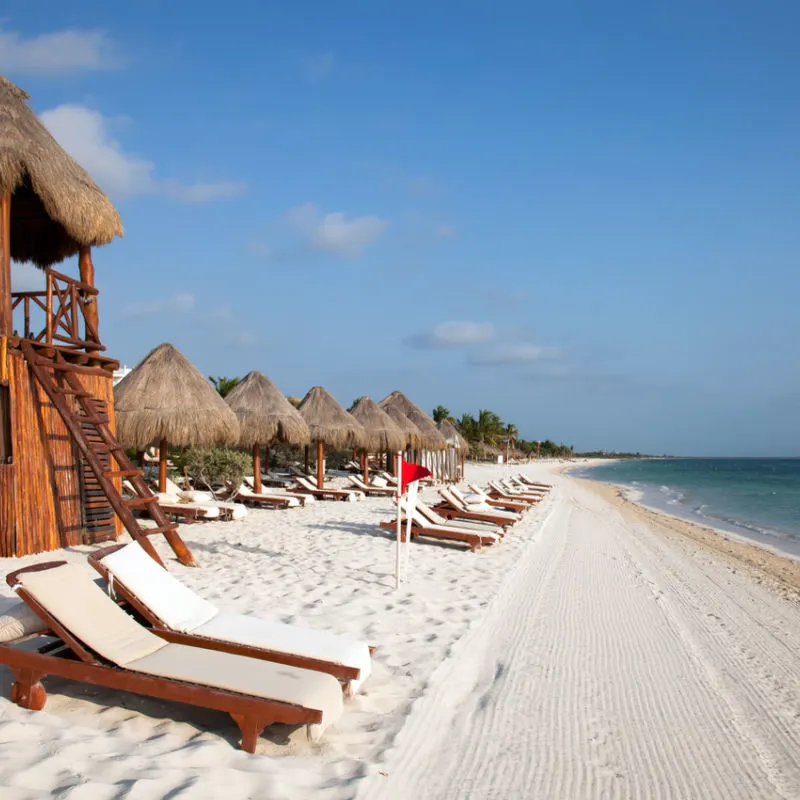 A red flag on display in a Cancun beach with sun chairs 