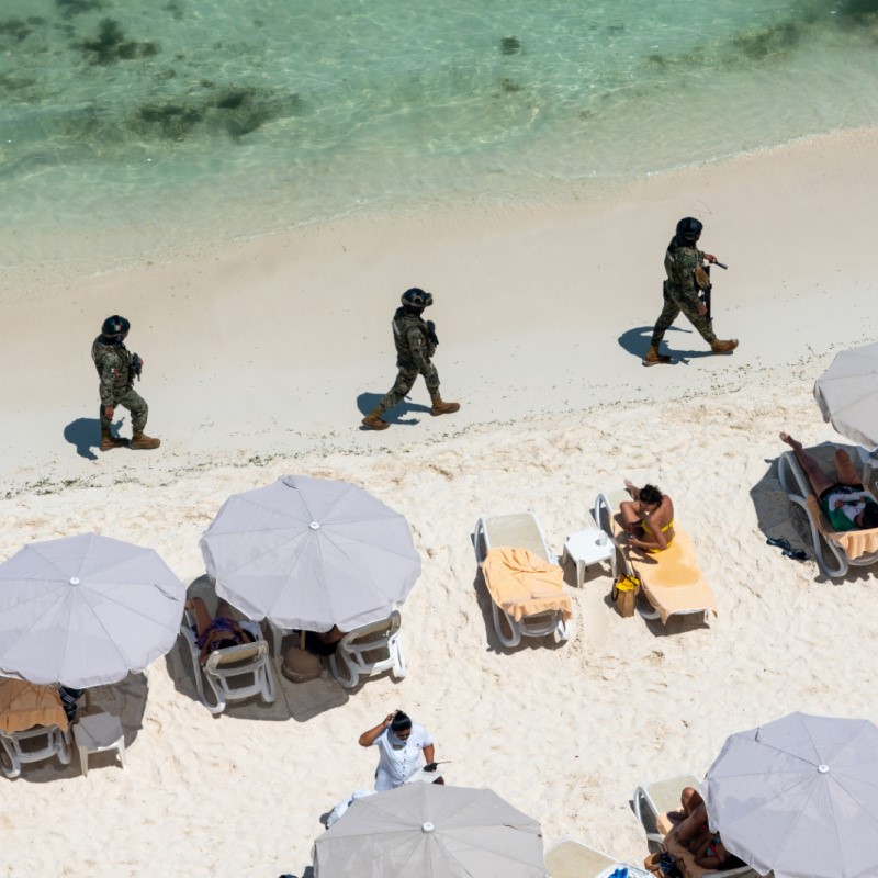 Security Officials Walking Pasts Tourists on a Beach in Cancun