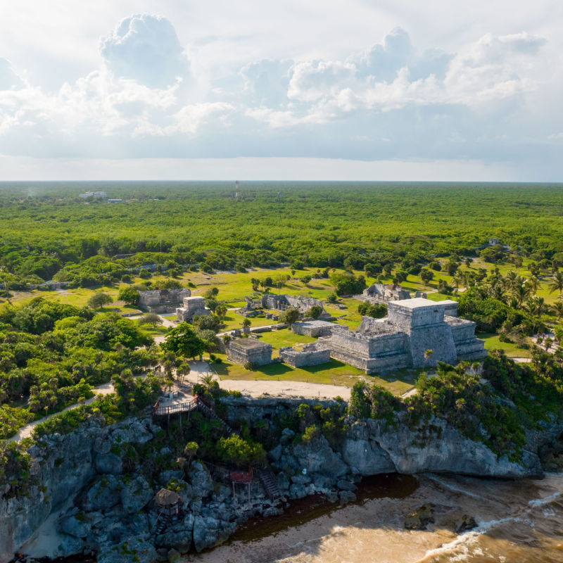 Aerial view of the Tulum Archeological Site with greenery in background 