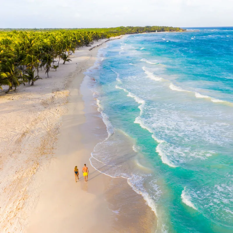 A couple walking on a beautiful white-sand beach in Tulum