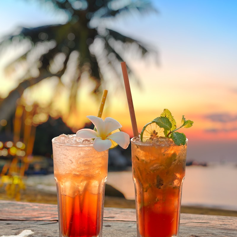 Bebidas con una playa brumosa y puesta de sol.