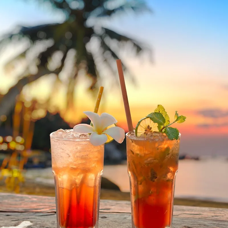 drinks with blur beach and sunset in background.