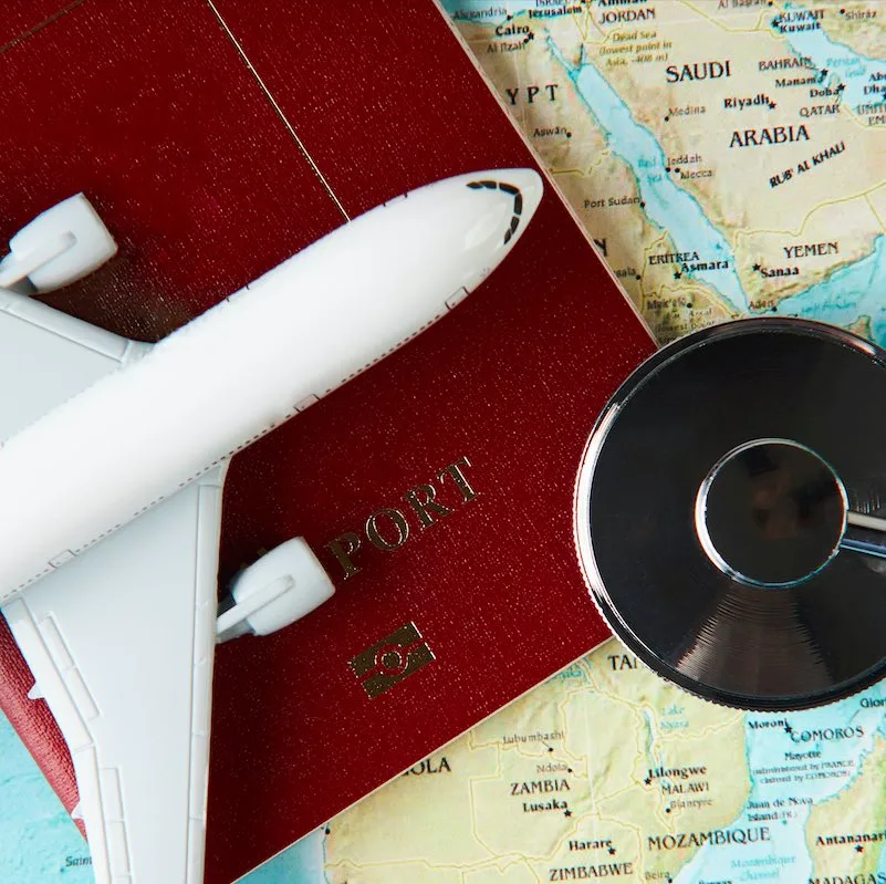 Medical travel concept with stethoscope passport document and airplane on world map background.