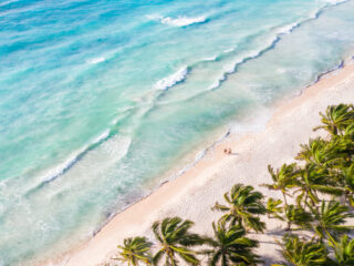 Aerial view of couple walking down Tulum beach