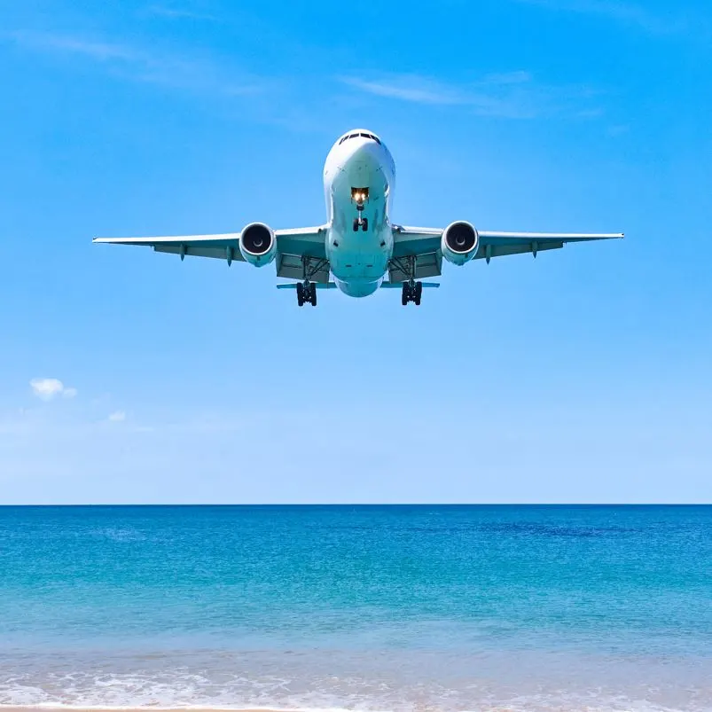 airplane coming into land in Mexican Caribbean over the ocean.