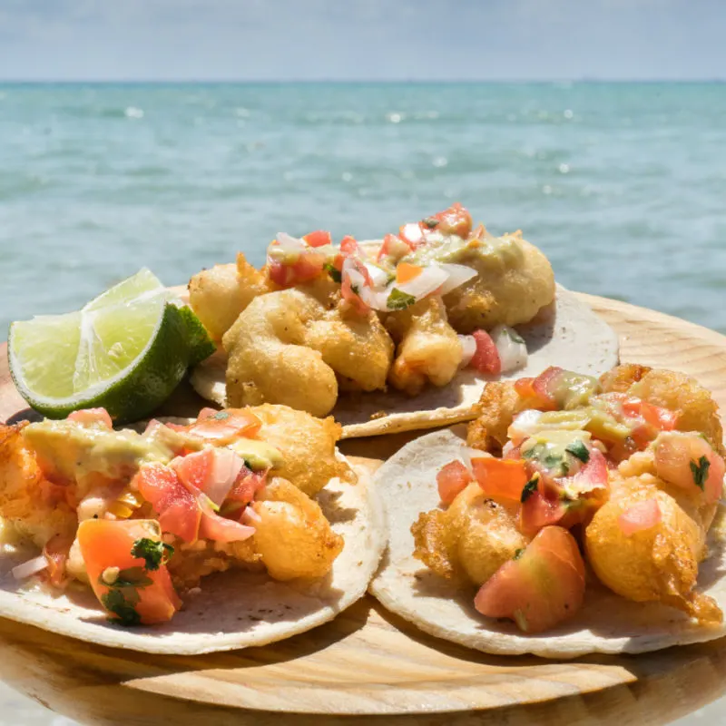 A portion of fish tacos by the sea on a Cancun beach